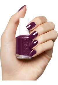 Vernice per unghie Essie in una tonalità di viola scuro, tenuta in una mano. La boccetta presenta un tappo bianco e l'etichetta è trasparente. Le unghie sono smaltate e lucide.