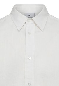 Camicia bianca in lino con colletto classico, chiusura frontale con bottoni e tessuto texturizzato, che mette in evidenza un design pulito e minimalista.