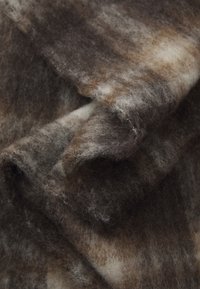 Tissu en laine avec une surface douce et texturée ; présente un mélange de couleurs marron, gris et crème avec un motif marbré.
