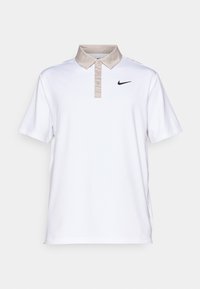 Polo branco com colarinho bege e três botões, apresentando um pequeno logótipo preto da Nike no lado esquerdo do peito. Textura de tecido suave.