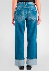 Jeans de mezclilla azul claro con corte recto, que presentan una cintura alta, grandes bolsillos traseros con un diseño de zigzag y dobladillos enrollados.