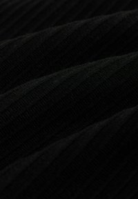 Tuvuma tuvuma melnā ribota adīta auduma ar mīkstām krokiem un smalku tekstūru.