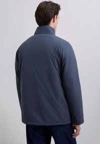 Miestna tmavomodrá, polstrovaná bunda s vysokým golierom, hladkou textúrou a rovný strih, zobrazená zozadu s minimálnym detailingom.