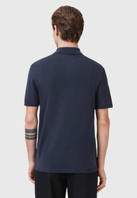 Marineblauw polo shirt met korte mouwen, gestructureerde stof en een klassieke kraag. Heeft stikdetails op de schouders.