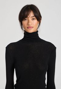 Schwarzer Rollkragenpullover aus weichem, leichtem Stoff; verfügt über ein tailliertes Design mit langen Ärmeln und hohem Kragen.