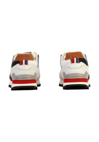 Zapatillas blancas y marinas con detalles en marrón, que cuentan con una suela a rayas rojas, un cuello acolchado y una pestaña en el talón de contraste con detalles en azul y rojo.