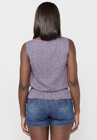 Mouwloze top in een roze en marineblauw bloemenpatroon met een peplum taille, gecombineerd met denim short met gestikte achterzakken.