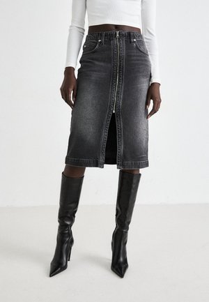 Black denim midi skirt with a front zipper, five pockets, and a fitted waist. Paired with knee-high black stiletto boots.