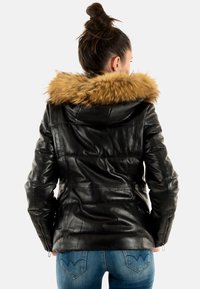 Veste en cuir noir avec col en fausse fourrure, poignets zippés et coupe ajustée. Le dos présente une texture matelassée et une taille cintrée.