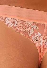 Perzische kanten string met geborduurd bloemenpatroon, voorzien van een transparante, rekbare tailleband en delicate geschulpte randen.