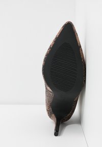 Scarpa con tacco a stiletto a punta in stampa pitone marrone con superficie testurizzata. La suola in gomma nera presenta scanalature orizzontali per una migliore aderenza.
