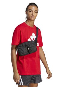 Borsa a tracolla nera in nylon con due tasche con zip, indossata a spalla, che presenta una superficie testurizzata e una tracolla regolabile.