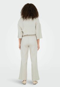 Ensemble deux pièces gris clair, texturé, avec un haut ample et oversized et un pantalon à taille élastique, doté de jambes larges et d'accents de design simples.