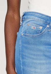 Světlé modré džíny z denimu s vysokým pasem, klasickým pětipocket designem a decentními švy. Obsahují malou logovou nášivku na přední kapse.