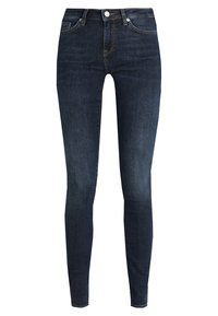 Jeans ajustados de color azul oscuro con cinco bolsillos, cierre de botón y un ligero desgastado en los muslos y las rodillas.