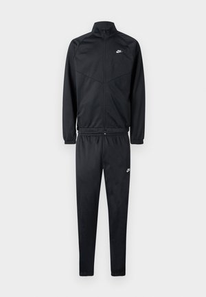 Svart träningsdräkt av slät tyg; består av en jacka med dragkedja och hög krage samt matchande byxor med elastisk midja. Nike-logotyp i vitt.