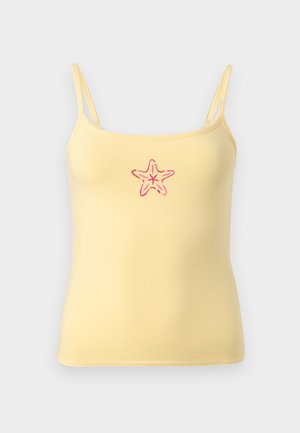 Gul spaghetti-topp med tynne stropper og et lite rødt sjøstjernemotiv brodert midt foran.