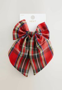 Punainen ruutukuosinen hiuspanta, joka on valmistettu sileästä kankaasta, jossa on mustia, keltaisia ja sinisiä yksityiskohtia. Kiinnitetty keskeltä, ja siinä on suuret silmukat ja nauhat.