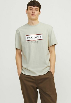 Hellgrünes Baumwoll-T-Shirt mit kurzen Ärmeln, das einen zentralen grafischen Druck in Schwarz und Rot zeigt, auf dem "JACK & JONES ORIGINALS" steht.