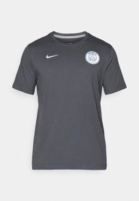 T-shirt grigio a maniche corte realizzato in morbido tessuto, con colletto rotondo, un logo Nike bianco e un logo circolare di Parigi sul lato sinistro del petto.