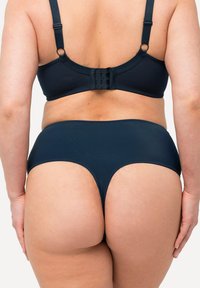 Ensemble de soutien-gorge bleu foncé et de culotte taille haute en tissu lisse. Le soutien-gorge présente des bretelles ajustables et une fermeture à crochets au dos.