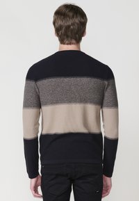 Gestreifter Strickpullover in Marineblau, Beige und Grau mit langen Ärmeln und Rundhalsausschnitt. Horizontale Farbblöcke und gerippte Bündchen.