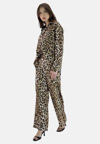 Monos de leopardo confeccionado en tela suave, con mangas largas y capucha con cordón. Combinado con sandalias de tacón negro.