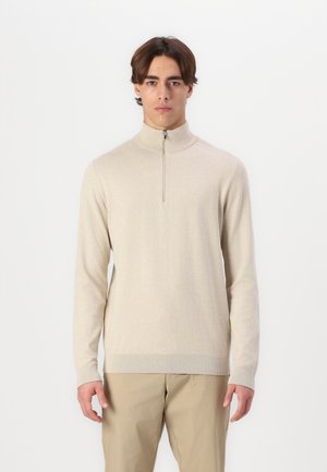 Suéter beige de cuello alto con media cremallera, puños y dobladillo acanalados, hecho de un material suave. Diseño sencillo y ajustado, sin patrones.