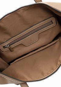 Beige textured leather bag interior with a zippered pocket and a flat compartment. Soft fabric lining in a lighter brown tone.