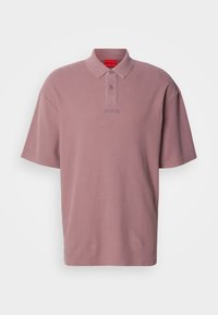 Πόλο μπλουζάκι με κοντά μανίκια σε απαλό ροζ χρώμα, κατασκευασμένο από υφασμάτινη υφή. Διαθέτει γιακά, δύο κουμπιά και διακριτική λεπτομέρεια λογότυπου στο ίδιο χρώμα.