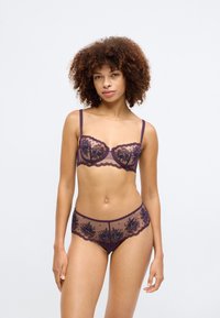 Lace lingerie set in deep purple, featuring floral embroidery, sheer fabric, underwire bra with adjustable straps, and matching sheer briefs.