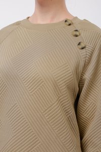 Maglione khaki con un motivo testurizzato di linee in rilievo. Presenta un collo a costine e tre bottoni decorativi beige sulla spalla sinistra.