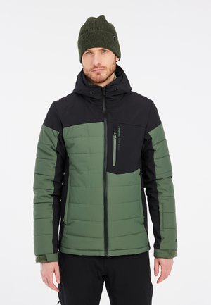 Chaqueta acolchada en verde y negro con un bolsillo en el pecho con cremallera, capucha y puños elásticos. El material parece resistente con una textura acolchada.