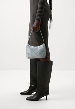 Pequeño bolso azul cubierto de rhinestones con forma curva y una asa corta, combinado con botas de cuero negras hasta la rodilla.