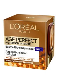 Crème de nuit Age Perfect de L'Oréal dans une boîte dorée avec un motif de nid d'abeille, comportant du texte en blanc et violet. Contient du miel de Manuka et du calcium B5.