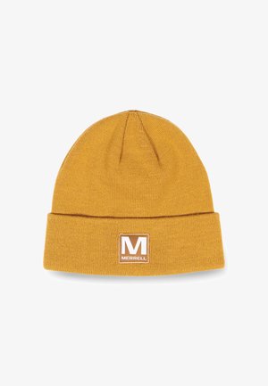 Gorro de punto color mostaza con doblez en el puño y una etiqueta cuadrada marrón que presenta la letra blanca "M" de Merrell. Textura suave, forma ajustada.