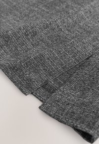 Pilka tekstilė su reljefine paviršiaus tekstūra, kurioje matomas austas raštas. Kraštai nėra apdirbti, pabrėžiantys audinio žaliavos išvaizdą.