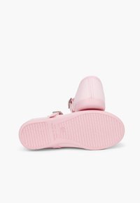 Sandalias rosas con un upper de textura suave, hebilla ajustable y suela de goma estriada. Presenta marcas que indican "Hecho en España".