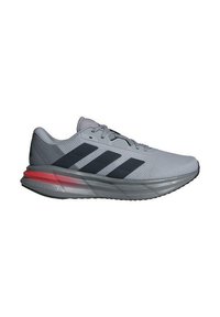 Scarpa sportiva grigia chiara con tomaia in rete, strisce nere e suola texturizzata. Presenta un accento rosso sul tallone e un'intersuola ammortizzata.