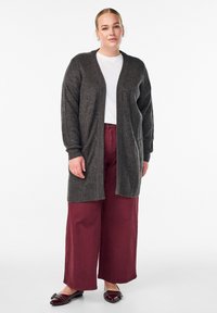 Šedý rebrovaný kardigán s otvoreným predným dielom, dlhými rukávmi a dvoma vreckami, skombinovaný s bordovými širokými nohavicami a lesklými čiernymi balerínkami.