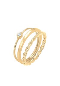 Anelli impilabili in tono oro con una banda liscia, design attorcigliato, e un anello accentuato da una pietra chiara. Combinazione di più texture e stili.