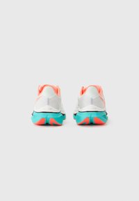 Zapatillas deportivas blancas con textura en la parte superior, acentos en coral vibrante en el talón y una suela turquesa con agarres estampados.