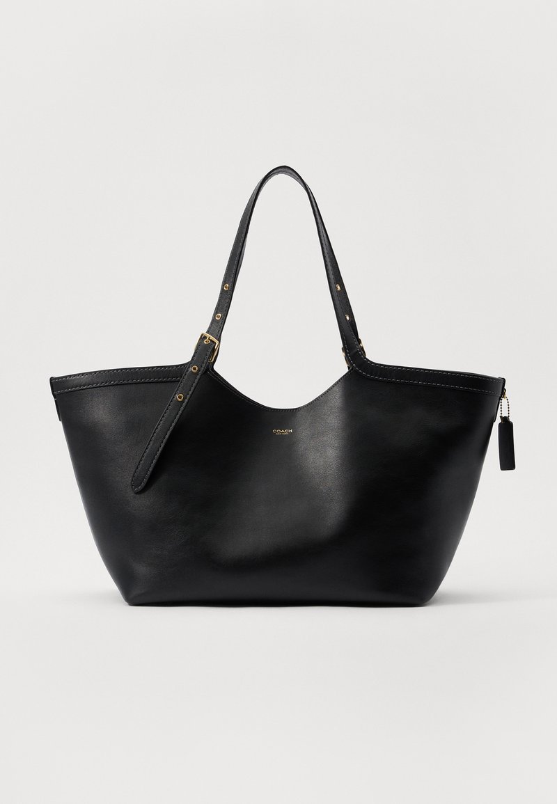 Sac tote en cuir noir avec une forme structurée, deux anses et des accents en métal doré. Présente une texture lisse et une étiquette décorative.