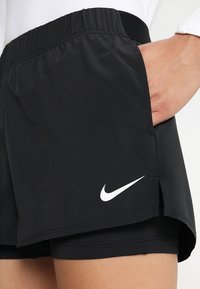 Shorts deportivos negros con cinturilla elástica y bolsillos laterales. Los shorts cuentan con un logo blanco de Nike y una textura ligera y suave.