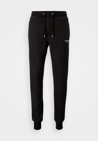 Black sweatpants in soft fabric. Features an elastic waistband with drawstring, ribbed cuffs, and white logo text on the left thigh.