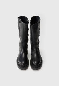 Botas de cuero negro hasta la rodilla con punta redondeada, lados texturizados, botones decorativos y una suela gruesa.
