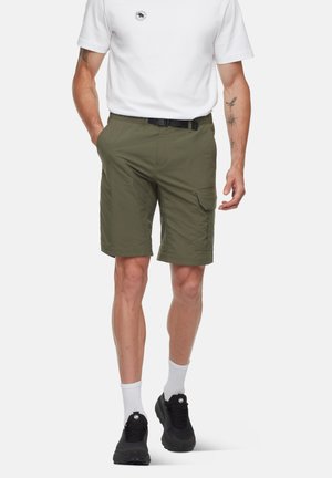Shorts cargo verts olive avec une ceinture, dotés de poches latérales et d'une coupe décontractée. Portés avec un t-shirt blanc et des chaussures de sport noires.