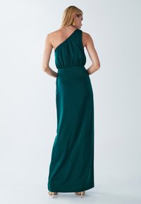 Długa, turkusowa sukienka maxi na jedno ramię z dopasowaną talią, lekkim materiałem i gładką teksturą. Posiada prosty, elegancki krój bez wzorów.