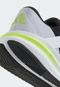 Szare i czarne buty sportowe z limonkowymi akcentami, z teksturowaną cholewką, wyściełaną podeszwą środkową oraz wzorzystą gumową podeszwą.