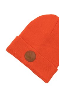 Pomarańczowa dziana czapka beanie z podwiniętym brzegiem oraz okrągłą skórzaną naszywką z logo. Gładka textura, lekki materiał.
